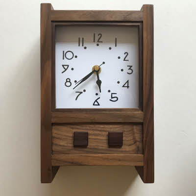 This is a small mantle clock in American Black Walnut with an Arts and Crafts style face and small rosewood squares.