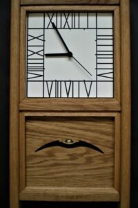 This large oak wall clock with a pendulum, was inspired by a Mackintosh chair design and the face of a clock in the Hill House.