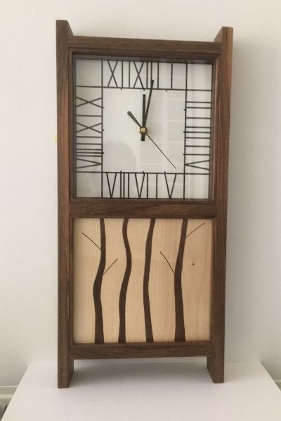 This is a large wall clock which has a Mackintosh inspired face and a contrasting panel of oak and sycammore in a woodland design.
