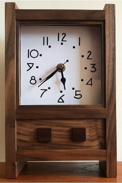 This is a small mantle clock in American Black Walnut with an Arts and Crafts style face and small rosewood squares.