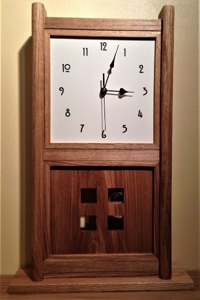The wall clock features a pendulum behind the four squares in the Mackintosh style, the face is also in a Mackintosh font.